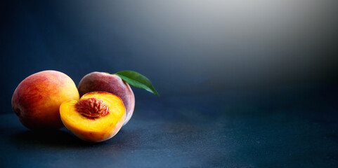 Fresh peaches and split with leaves on black background.