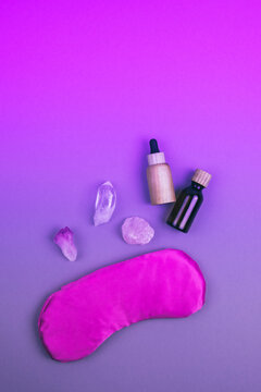 Top View Of Gemstones Crystal Minerals, Pink Eye Pillow, Glass And Wooden Bottles For Essential Oils Over Neon Colored Background. Place For Text. Relaxation And Meditation Concept.