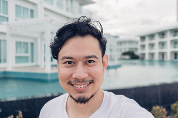 Happy face of Asian man selfie himself with luxury resort in vacation.