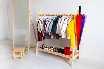 Dressing closet with autumn clothes arranged on hangers. Colorful wardrobe of newborn, kids, toddlers, babies full of all clothes. montessori wardrobe