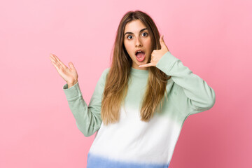 Young woman over isolated pink background making phone gesture and doubting