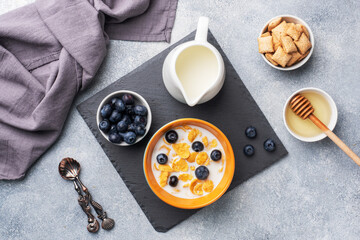 Corn flakes made from natural cereals with fresh blueberries, honey and milk. The concept of a healthy wholesome Breakfast. copy space Grey concrete background