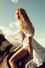 beautiful blonde woman riding a horse in summer day. Romantic fashion style