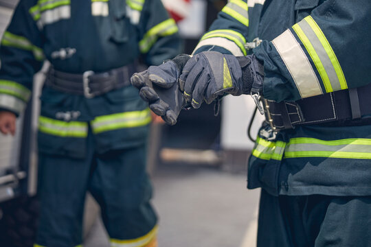 Portrait Of Strong Hands Of Firefighter Standing In Front Of Another Man