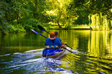 Two people in a blue kayak row on the river in the Spreewald.
