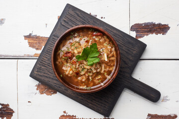 Vegetarian soup kharcho with rice and vegetables. Garlic hot pepper tomatoes. Copy space. Wooden rustic background, plates made of natural bamboo.