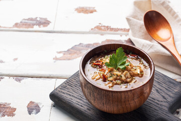 Vegetarian soup kharcho with rice and vegetables. Garlic hot pepper tomatoes. Copy space. Wooden rustic background, plates made of natural bamboo.