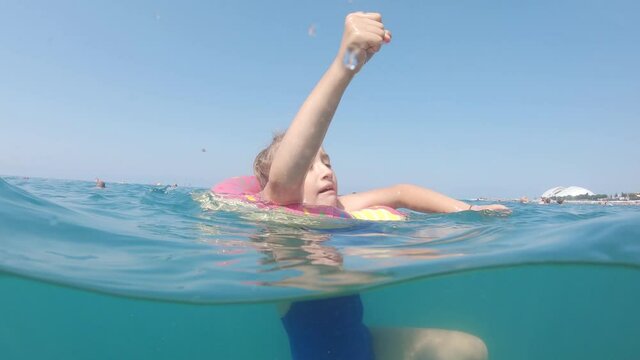 Cute child girl on air mattress in sea. Family vacation concept.
