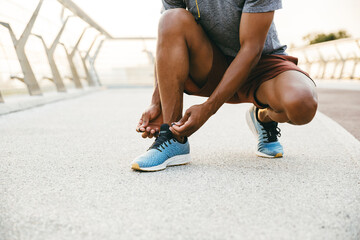 Sporty african man tying shoelace