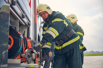 Fototapeta premium Firefighter installing equipment on the fire machine