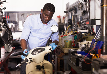 Confident man worker repairing motorcycle in workshop. High quality photo