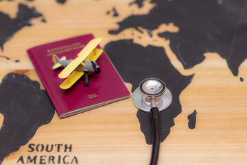 Medical travel concept. stethoscope passport document and toy airplane on wooden world map background.