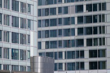 An abstract view of two urban buildings with large glass windows and white walls.