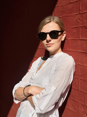 Outdoor summer city lifestyle portrait of young trendy dressed blonde happy woman in sunglasses having fun outdoor in the city ready for travel