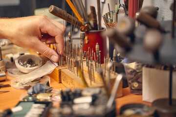 Male hand choosing a bur among the toolkit