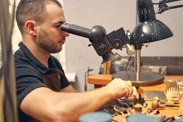Serious male jeweler using an optical tool
