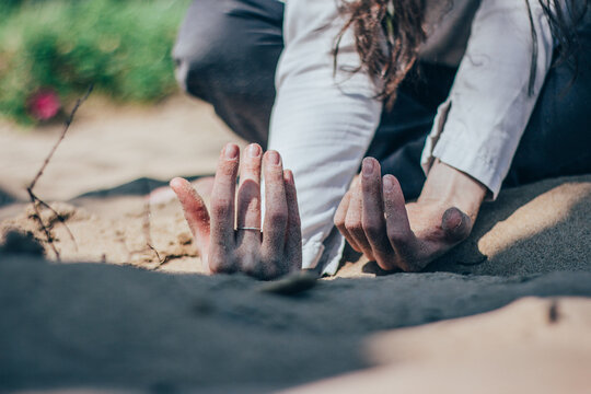 Close-up Of Woman Hands On Sand
