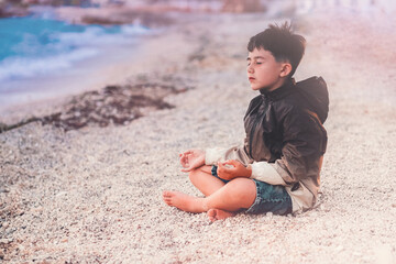 little boy Child meditating on the beach