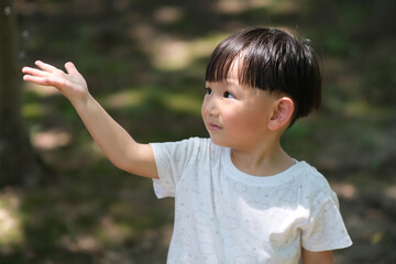 close up one Asian toddler reaching out hand to the sunshine. blur background