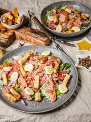 Close-up two servings of Caesar salad with salted salmon, romaine lettuce, quail eggs and garlic croutons. Vertical shot