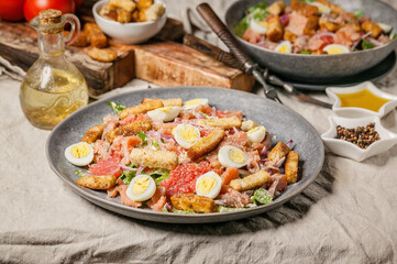 Close-up Caesar salad with red fish, romaine lettuce, quail eggs, garlic croutons and olive oil. Horizontal shot