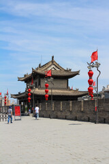 The great City wall of Xian city with a watchtower and red lanterns against a blue sky with clouds. Xian. China...