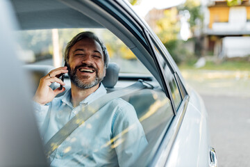 Businessman on a back seat. Grey hair and grey beard.