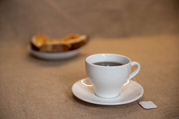 a white Cup of tea and a plate of sandwiches on the table