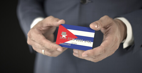 Businessman holding plastic bank card with printed flag of Cuba, fictional numbers