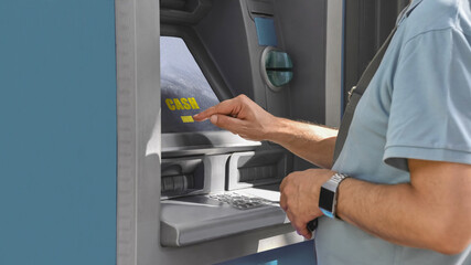 Male hands using a touchscreen to withdraw money from a cash machine.