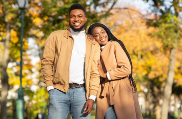 Happy african american couple posing together over autumn park background