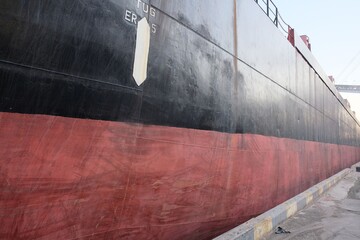 View of cargo ship side hull shell plating of red and black color