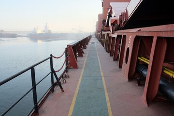 Main weather deck from portside of the vessel with holds coamings and guard rails