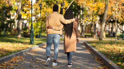 Rear view of romantic black couple walking on pathway in park