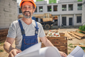 Man in a hard hat holding a house plan