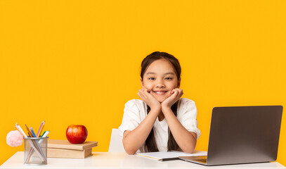 Smiling Chinese School Girl Sitting At Laptop, Studio Shot