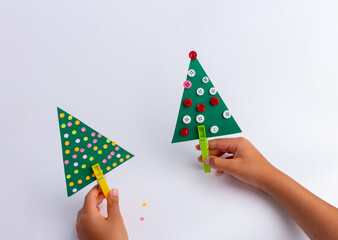 christmas craft for kids. diy, hands making easy paper holiday tree, holiday art activity. Christmas tree concept.