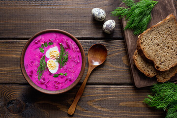 Delicious, healthy cold beetroot soup, decorated with egg and dill on a wooden table. Top view