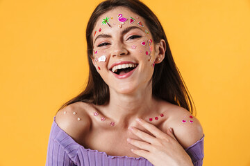 Image of young joyful woman with stickers on face laughing at camera