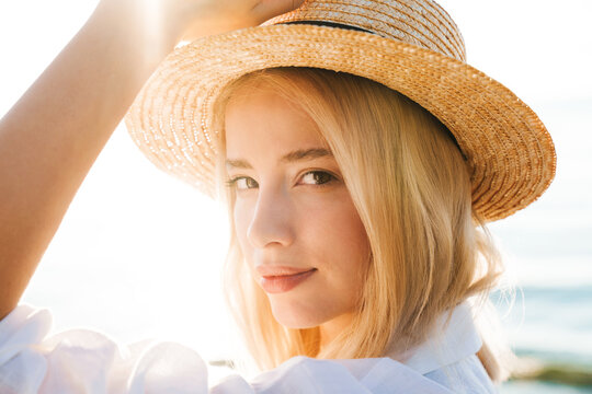 Image of charming blonde woman in straw hat posing and looking at camera