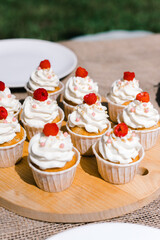 cupcakes with cream on a wooden tray outside