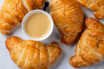 Cup of coffee and croissants on concrete background. French breakfast. Top view.