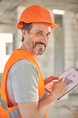 Bearded man in a helmet holding blueprints