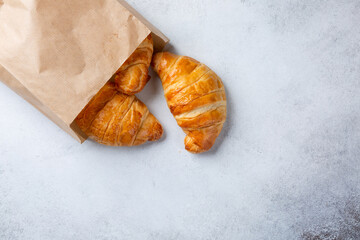 Croissants in paper bag on concrete background. Top view, copy space.