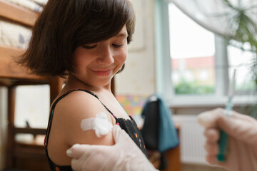 Girl with plaster on shoulder from the injection.