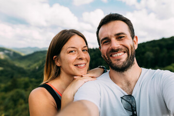 Fototapeta premium Young couple taking a selfie in the mountains