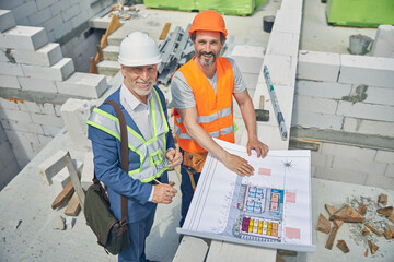 Cheerful senior man and a builder looking upwards