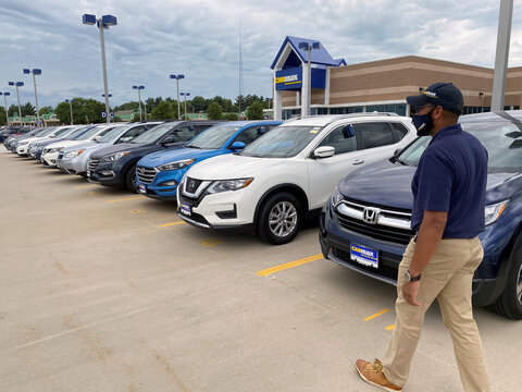 Brandon Parrum, general manager of CarMax's Des Moines store, walks past vehicles that customers can arrange to buy online and collect at the store using "contactless" curbside pickup