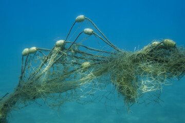 Lost fishing net with buoys lies underwater on the seabed on blue water background. Becici, Budva Municipality, Montenegro - obrazy, fototapety, plakaty