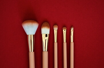Set of makeup brushes on a red  background. Top view point, flat lay. Beauty and trend life style concept.